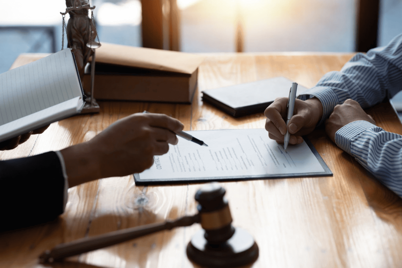 Two individuals reviewing and signing legal paperwork related to a Public Liability Claim.